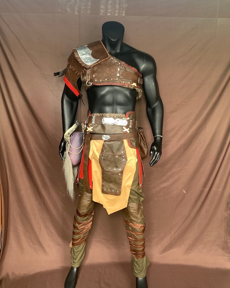 Puede incluir: Un traje de cuero marr&oacute;n con un acento de metal plateado, un cintur&oacute;n de cuero marr&oacute;n con acentos de metal plateado y pantalones de cuero marr&oacute;n con correas de cuero marr&oacute;n. El traje est&aacute; en un maniqu&iacute;.