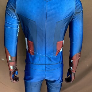 May include: A blue and red spandex costume with a star on the chest. The costume has long sleeves and pants.