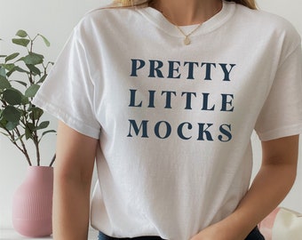 Könnte beinhalten: Weißes T-Shirt mit dem marineblauen Text "PRETTY LITTLE MOCKS". Das Oberteil hat einen Rundhalsausschnitt und kurze Ärmel. Das Model trägt eine dunkelblaue Jeans.