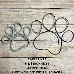 May include: Two paw print shapes, one made of gray yarn and the other made of black wire. The yarn paw print is 6 inches and the wire paw print is 8 inches. The text "PAW PRINTS 6 & 8 INCH SIZES EXAMPLE ITEMS (NOT INCLUDED WITH PURCHASE)" is below the paw prints.