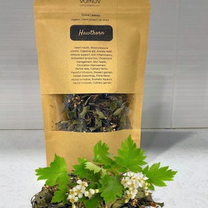 May include: A brown paper bag with a label that reads "VOMOV vomovplants.com Dried Leaves organic hand-picked | air-dried Hawthorn Heart health, Blood pressure control, Digestive aid, Anxiety relief, Immune support, Anti-inflammatory, Antioxidant properties, Cholesterol management, Skin health, Circulation improvement, Herbal teas, Culinary herbs, Flavorful infusions, Dessert garnish, Herbal seasonings, Floral flavour, Herbal remedies, Aromatic liqueurs, Herbal tinctures, Culinary garnish"  The bag is open and spilling out dried hawthorn leaves and flowers.