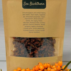 Peut inclure: Un sac en papier kraft contenant des baies d'argousier avec une fenêtre transparente, une branche de baies orange et un tas de baies séchées. Le sac porte l'inscription "Sea Buckthorn" et énumère les bienfaits pour la santé.