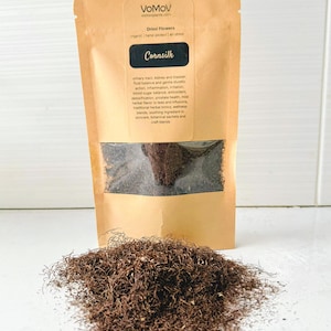 Könnte beinhalten: Ein brauner Papiersack mit getrocknetem Maisseide mit einem transparenten Fenster und einem Haufen Maisseide vor dem Sack. Der Sack hat ein Etikett mit dem Text "Cornsilk" und Informationen über die Verwendung des Produkts. Das Produkt ist biologisch, handverlesen und luftgetrocknet.