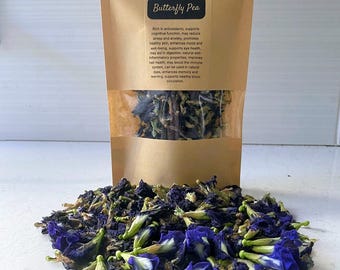 May include: A tan stand-up pouch labeled VoMoV containing dried butterfly pea flowers. The label lists the product as organic, hand-picked, and air-dried. A pile of deep blue and green dried butterfly pea flowers is spread out in front of the pouch.
