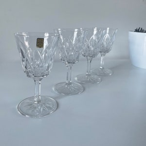 May include: Set of four clear glass stemmed wine glasses with a cut crystal design.