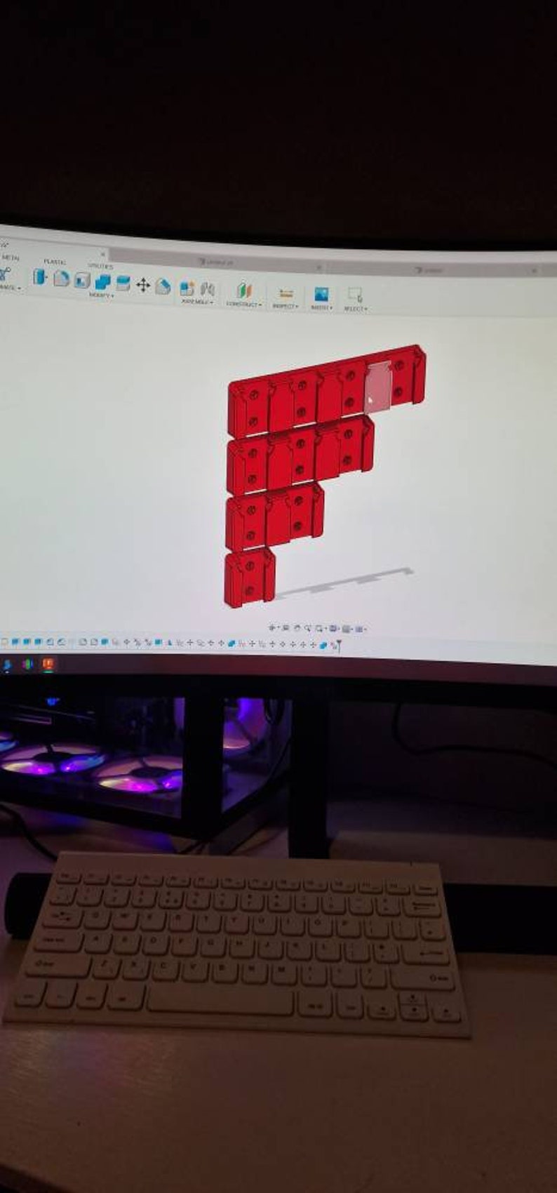 Puede incluir: Un monitor de ordenador muestra un modelo 3D de un componente modular rojo. El dise&ntilde;o est&aacute; dispuesto en una configuraci&oacute;n vertical escalonada. Un teclado blanco est&aacute; en primer plano.