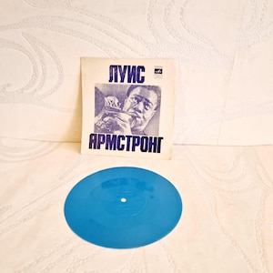 Könnte beinhalten: Eine Vintage-Schallplatte mit einem blauen Label. Das Plattencover zeigt ein Schwarzweißfoto von Louis Armstrong, der Trompete spielt. Der Text auf dem Cover lautet "Louis Armstrong".