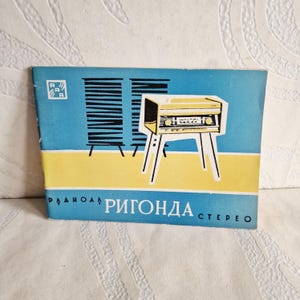 Puede incluir: Un folleto vintage con un esquema de color azul y amarillo. La portada presenta una ilustración estilizada de una radio amarilla sobre patas blancas, con el texto "РИГОНДА СТЕРЕО" en blanco. El folleto tiene el logotipo "R R R" en la esquina superior izquierda.
