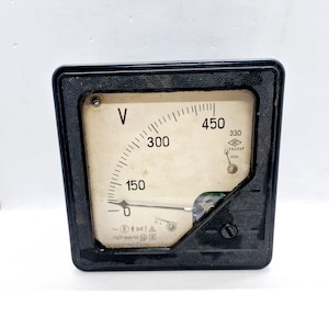 Puede incluir: Un voltímetro cuadrado negro vintage con una esfera color crema. El medidor muestra lecturas de voltaje de 0 a 450, con una aguja que indica el voltaje actual. La esfera tiene la letra "V" y otras marcas.
