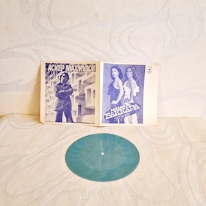 Könnte beinhalten: Eine Vintage-Schallplatte mit einem blauen Label. Das Plattencover zeigt ein Foto eines Mannes im Anzug und ein Foto von zwei Frauen. Der Text auf dem Cover lautet "Asker Mahmudov" und "Ansambl Bakkara - Ispolnenie".