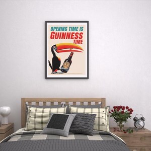 Puede incluir: Un p&oacute;ster enmarcado con un tuc&aacute;n y una botella de Guinness. El texto del p&oacute;ster dice "OPENING TIME IS GUINNESS TIME". El tuc&aacute;n tiene un gran pico naranja y amarillo. El p&oacute;ster est&aacute; colgado sobre una cama con almohadas y una manta.