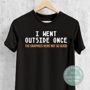 May include: Black t-shirt with white text that reads "I went outside once the graphics were not so good". The shirt has a tag that says "Water Based Inks Eco Non-Toxic PVC Free".