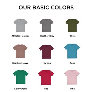 May include: Nine different color t-shirts displayed on a white background. The colors are: Athletic Heather, Heather Gray, Olive, Heather Mauve, Maroon, Aqua, Kelly Green, Red, and Pink.