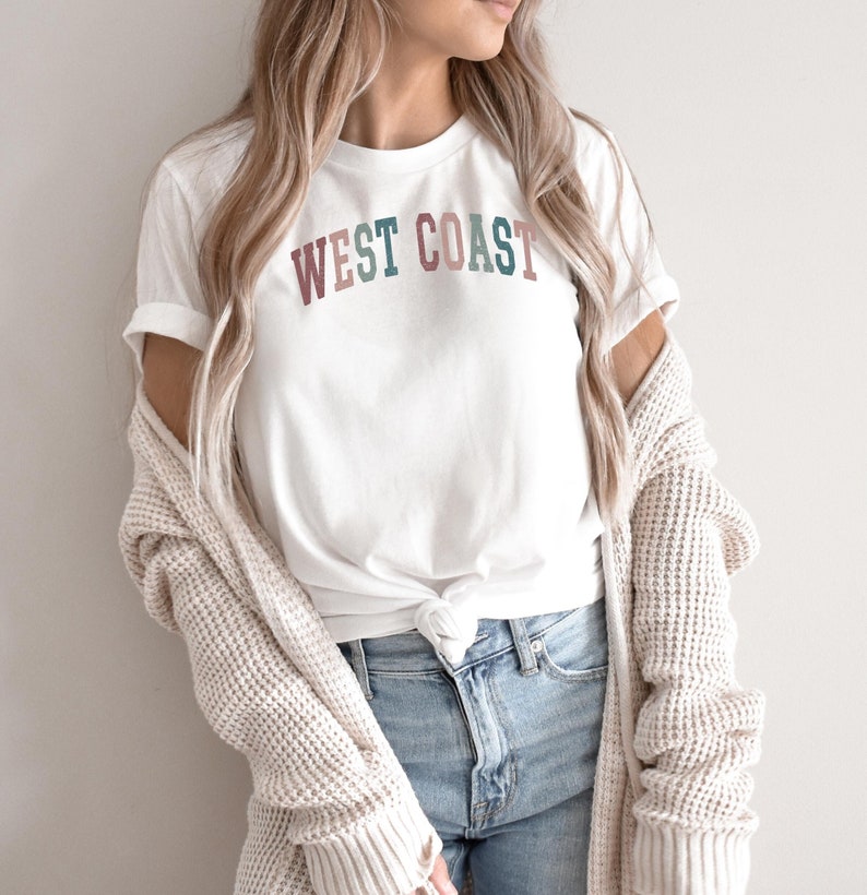 May include: A white t-shirt with the text "WEST COAST" in colorful letters. The letters are in shades of pink, green, and blue.