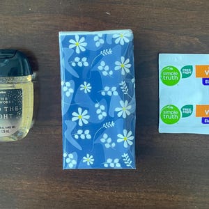 May include: A Bath & Body Works Into The Night anti-bacterial hand gel in a 1 fl oz bottle, a pack of tissues with a blue and white floral pattern, and two Simple Truth effervescent Vitamin C elderberry flavored dietary supplement packets.
