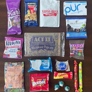 May include: A collection of various snack food packages including Kar's Sweet 'n Salty Mix, Planters Salted Peanuts, Swiss Miss Hot Cocoa, P&uuml;r Peppermint Gum, Brookside Dark Chocolate, Welch's Fruit Snacks, Act II Microwave Popcorn, Brach's Jelly Beans, Stellar Mini Pretzel Braids, Rice Krispies Treats, York Peppermint Pattie, Starburst, Skittles, and two Mamba fruit chews with three small round candies.