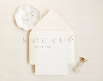 May include: A white card mockup with the text "MOCKUP 5x7" CARD" on a beige background. The card is surrounded by a white envelope, a small white dish with two clear gems, and a gold and white wax seal.