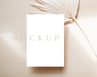 Puede incluir: Una maqueta de tarjeta blanca con el texto "MOCKUP 5X7" sobre un fondo beige con una hoja de palma seca.
