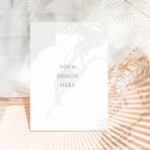 May include: A white card with the text "YOUR DESIGN HERE" on a light brown background with a white floral shadow.