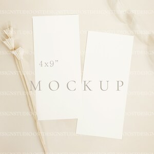 May include: Two blank white cards on a beige background with a dried flower arrangement. The larger card is 4x9 inches and the text "MOCKUP" is printed on the background.