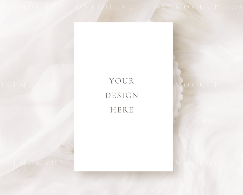 Pode incluir: Um mockup de cart&atilde;o branco com o texto "YOUR DESIGN HERE" em um fundo de tecido branco.