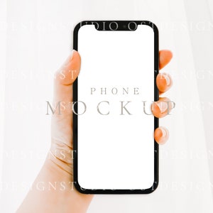 May include: A hand holding a black smartphone with a white screen. The text "PHONE MOCKUP" is displayed on the screen.