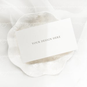 May include: A white card with the text "YOUR DESIGN HERE" on a white, textured, scalloped surface.
