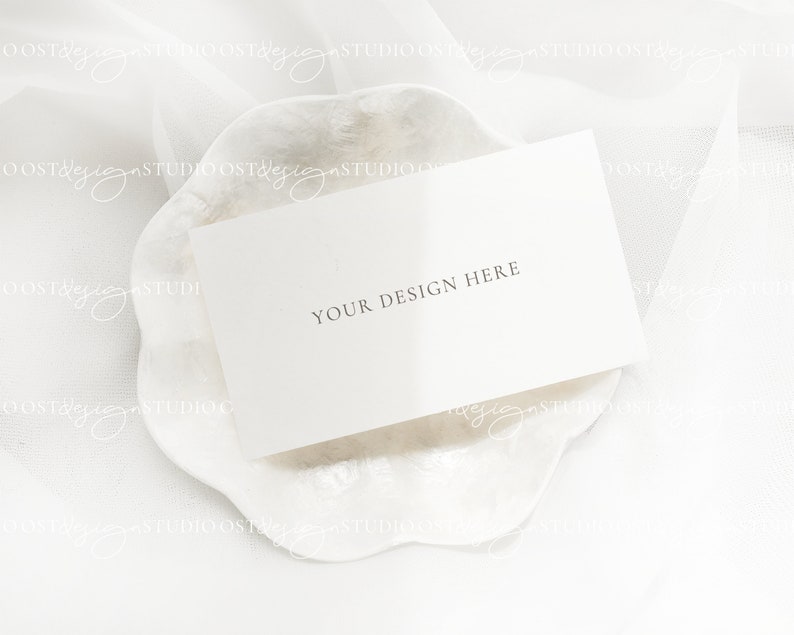 May include: A white card with the text "YOUR DESIGN HERE" on a white, textured, scalloped surface.