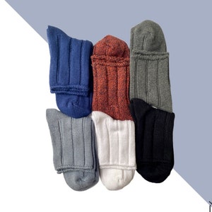 May include: Six pairs of socks in various colors, including gray, white, black, blue, and orange. The socks are folded and arranged in a row.