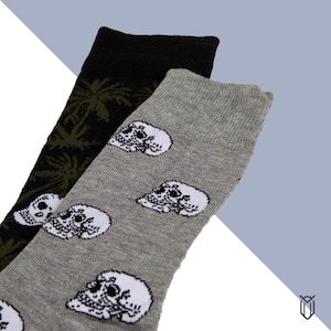 May include: Two pairs of socks. One pair is black with a green palm tree design. The other pair is gray with a white skull design.