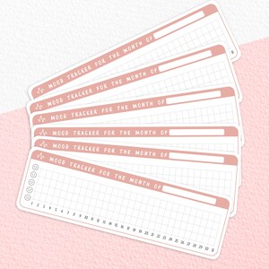 Puede incluir: Seis rastreadores de estado de &aacute;nimo rosa y blanco con el texto "MOOD TRACKER FOR THE MONTH OF" y una cuadr&iacute;cula de cuadrados para cada d&iacute;a del mes. El rastreador inferior tiene una columna de cinco emojis que representan diferentes estados de &aacute;nimo.