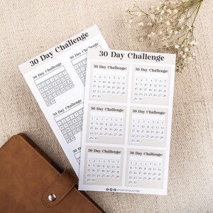 May include: A set of six printable 30-day challenge calendar stickers with a beige background and black text. Each sticker features a calendar grid with the numbers 1 through 30.