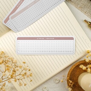 May include: A pink and white stress tracker with a grid of dots and numbers 1 through 31. The tracker is labeled "STRESS TRACKER".