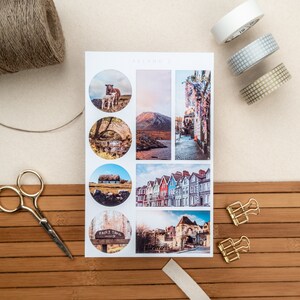 May include: A sheet of stickers featuring various images of Irish landscapes and architecture. The stickers are round and feature images of a sheep and lamb, a stone bridge, a thatched cottage, a row of colorful houses, a sign that reads "Fairy Trail", and a stone archway.