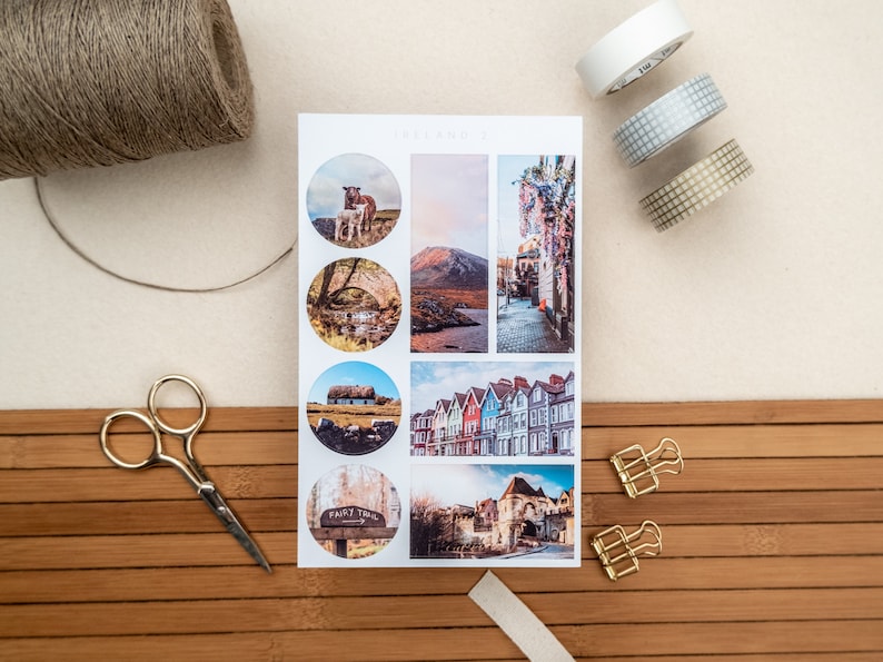 May include: A sheet of stickers featuring various images of Irish landscapes and architecture. The stickers are round and feature images of a sheep and lamb, a stone bridge, a thatched cottage, a row of colorful houses, a sign that reads "Fairy Trail", and a stone archway.