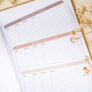 Puede incluir: Tres p&aacute;ginas de seguimiento de p&eacute;rdida de peso con un esquema de color rosa y blanco. Cada p&aacute;gina tiene columnas para la fecha, el peso, el cambio y las notas.
