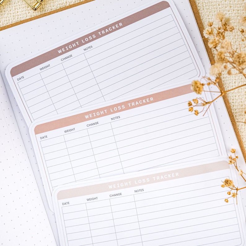 Puede incluir: Tres p&aacute;ginas de seguimiento de p&eacute;rdida de peso con un esquema de color rosa y blanco. Cada p&aacute;gina tiene columnas para la fecha, el peso, el cambio y las notas.