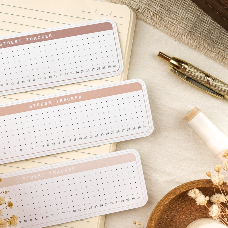 May include: Three pink and white stress tracker cards with black dots. Each card has the text "STRESS TRACKER" and numbers 1-31.