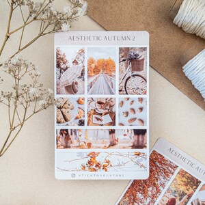 May include: A sheet of stickers with an autumn theme. The stickers feature images of a bridge, a bicycle, a cup of coffee, a book, pinecones, and fall leaves. The text "AESTHETIC AUTUMN 2" is at the top of the sheet. The text "STICKTOYOUSTORE" is at the bottom of the sheet.