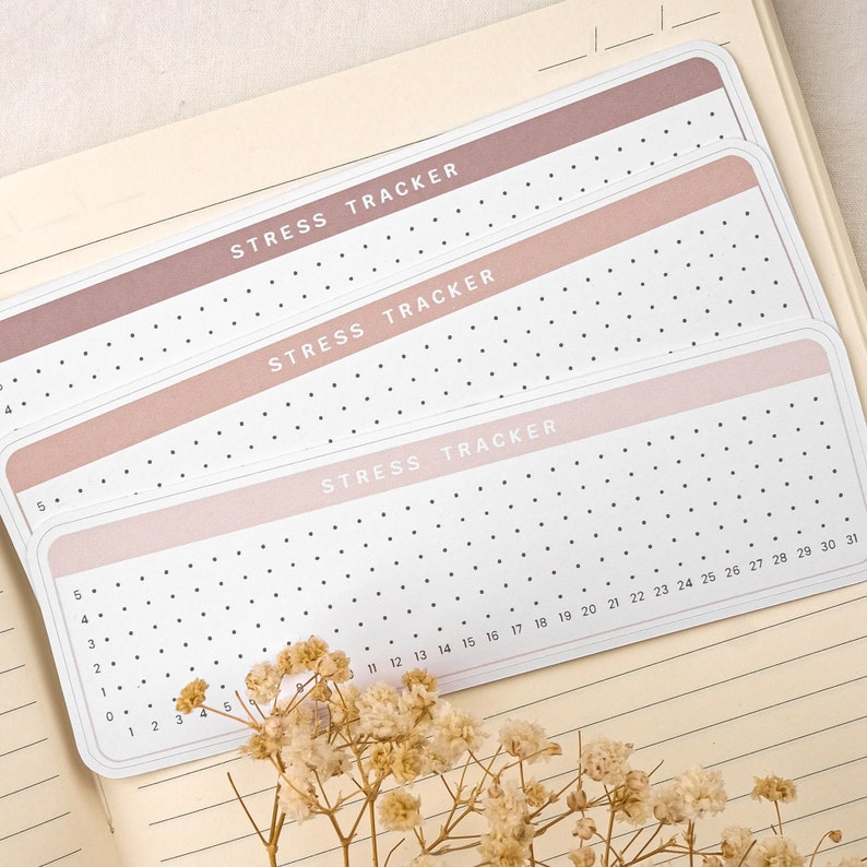 May include: Three pink and white stress tracker sheets with black dots and the text "Stress Tracker" printed on each sheet. The sheets are numbered from 0 to 31.
