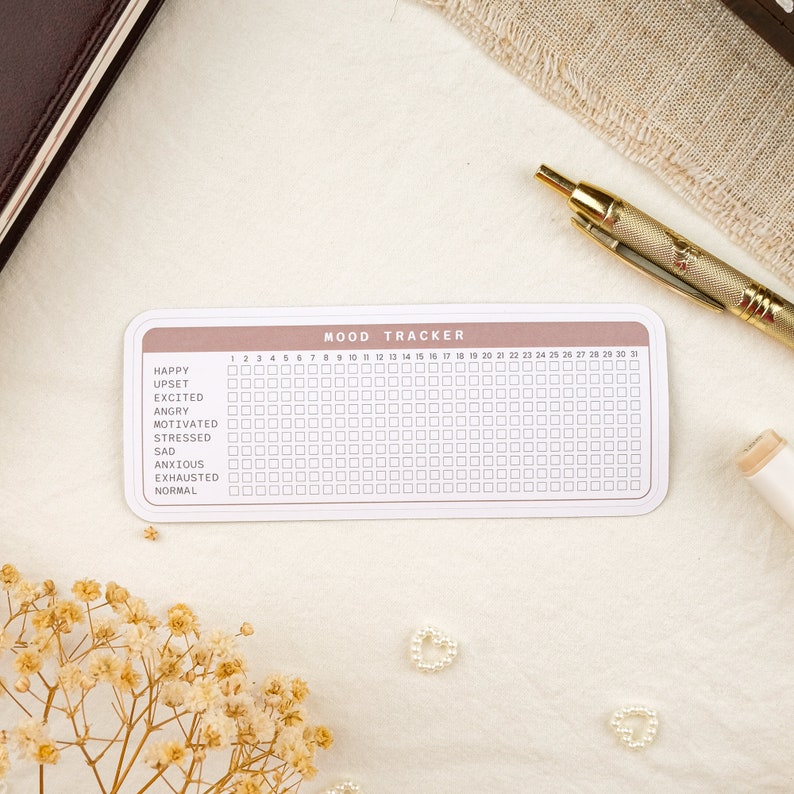 May include: A pink and white mood tracker with a grid of 30 squares for each day of the month. The tracker includes a list of moods: happy, upset, excited, angry, motivated, stressed, sad, anxious, exhausted, and normal.