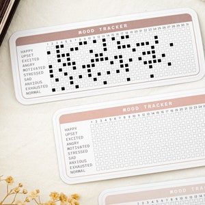 May include: A mood tracker with a pink and white color scheme. The tracker has a grid of squares with numbers 1 through 31 at the top. The left side of the tracker lists mood options: Happy, Upset, Excited, Angry, Motivated, Stressed, Sad, Anxious, Exhausted, and Normal.