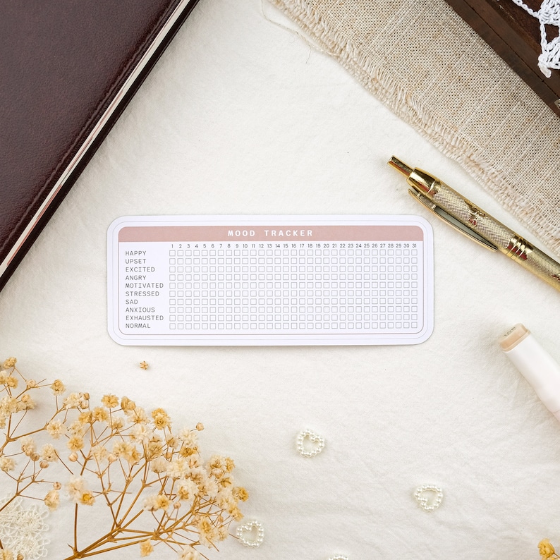 May include: A pink and white mood tracker with a grid of 31 squares for each day of the month. The tracker includes a list of moods: happy, upset, excited, angry, motivated, stressed, sad, anxious, exhausted, and normal.