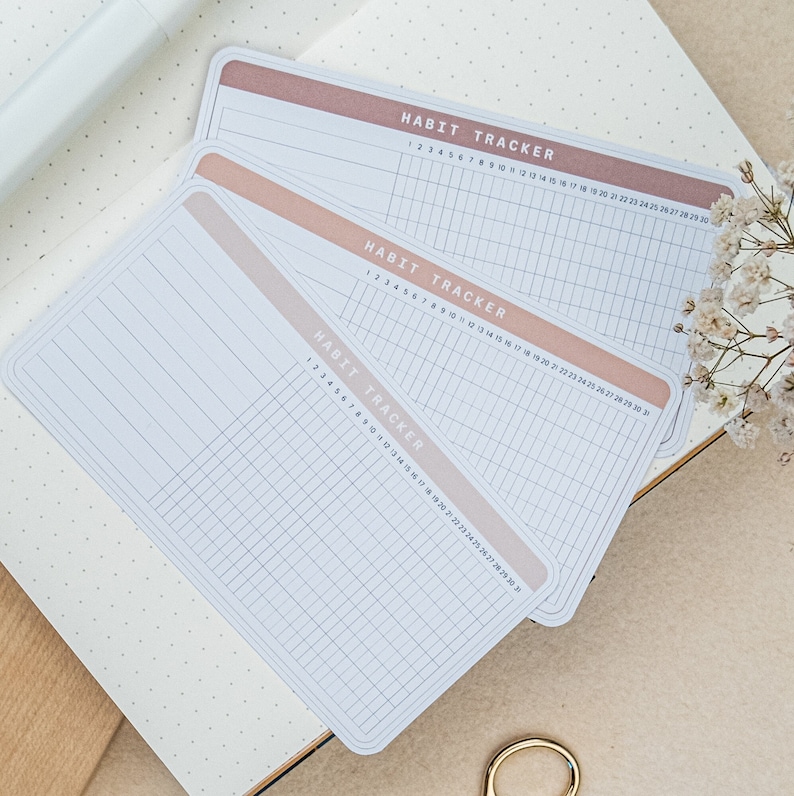 May include: Three white habit tracker sheets with a peach colored border. The sheets are labeled "Habit Tracker" and have numbered columns from 1 to 30.
