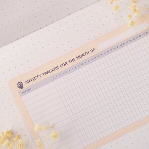 May include: A printable anxiety tracker for the month, featuring a brain icon and the word "Symptoms" at the top. The tracker has a grid with numbered days of the month and rows for tracking symptoms.