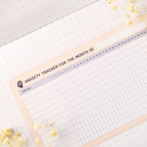 May include: A beige printable anxiety tracker for the month with a grid layout and the text "ANXIETY TRACKER FOR THE MONTH OF" at the top. The tracker has a column for symptoms and 30 columns for each day of the month.