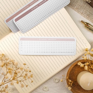 May include: A pink and white printable stress tracker with a grid of dots and numbers 1-30. The text "Stress Tracker" is printed at the top of the tracker.