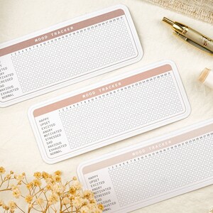 May include: Three printable mood trackers with a peach colored header and a white grid. The trackers have a list of moods including happy, upset, excited, angry, motivated, stressed, sad, anxious, exhausted, and normal. The trackers are numbered 1 to 31.
