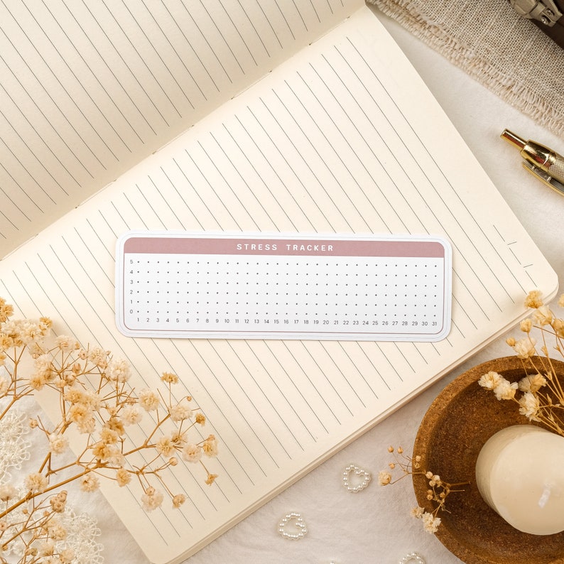 May include: A pink and white stress tracker with a grid of dots for marking stress levels. The tracker has the text "Stress Tracker" printed on it.