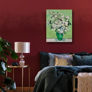 May include: A painting of a white flower bouquet in a green vase against a green background. The painting is framed and hanging on a red wall.